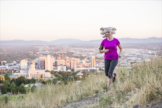 Caucasian woman running on hilltop over Salt Lake City