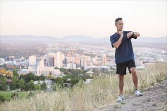 Mixed race man checking pulse on hilltop over Salt Lake City