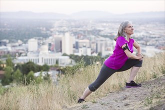 Caucasian woman stretching on hilltop over Salt Lake City