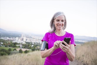 Caucasian woman using cell phone on hilltop