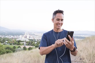 Mixed race man using cell phone on hilltop