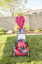 Caucasian man mowing lawn in backyard