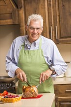 Caucasian man carving chicken in kitchen