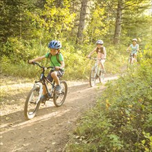 Caucasian mother and children riding mountain bikes