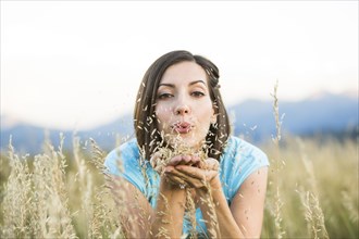 Caucasian woman blowing seeds in field