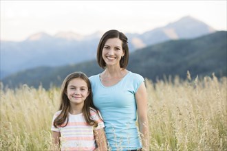 Caucasian mother and daughter smiling in field