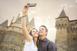 Caucasian couple taking selfie at castle