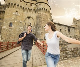 Caucasian couple running at castle