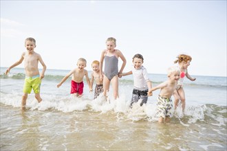 Caucasian children playing in waves on beach