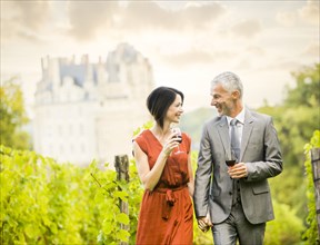 Caucasian couple enjoying wine in vineyard