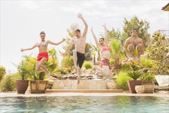 Friends jumping into swimming pool