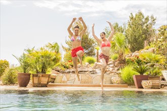 Caucasian women jumping into swimming pool
