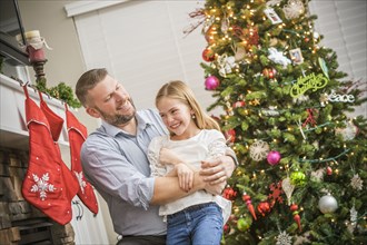 Caucasian father and daughter hugging near Christmas tree