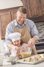 Caucasian father and daughter baking in kitchen