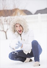 Caucasian woman throwing snowball in snow