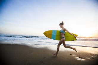 Caucasian woman carrying surfboard on beach