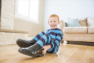 Caucasian boy wearing shoes of father in living room
