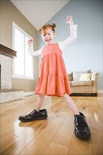 Caucasian girl wearing shoes of father in living room
