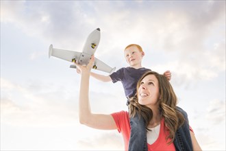 Caucasian mother and son flying toy airplane