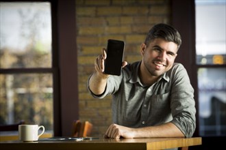 Caucasian man showing cell phone in cafe