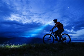 Silhouette of Caucasian man riding mountain bike at night
