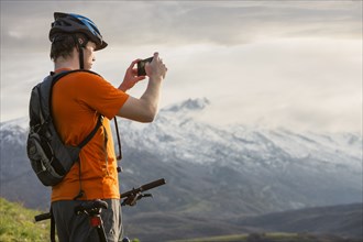 Caucasian man on mountain bike photographing scenic view