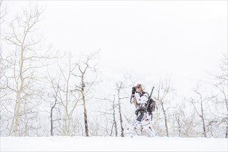 Caucasian woman hunting in forest using binoculars