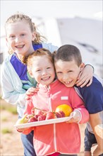 Caucasian boy and girls posing with fruit plate