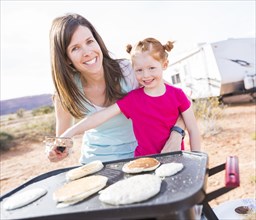 Caucasian mother and daughter making pancakes outdoors