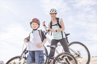Caucasian mother and son posing with mountain bikes