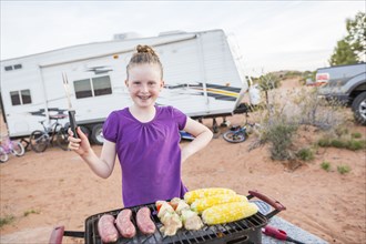 Caucasian girl cooking on grille while camping