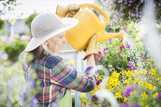 Caucasian woman watering flowers in greenhouse