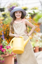 Caucasian girl holding watering can in greenhouse