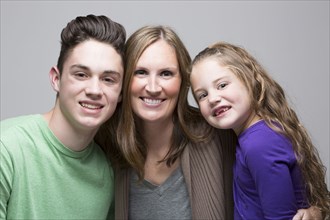Caucasian mother posing with smiling son and daughter