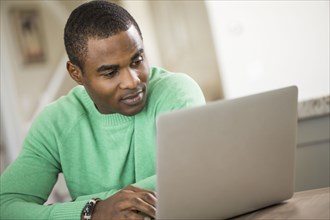 Black man sitting at table using laptop