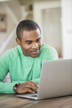 Black man sitting at table using laptop