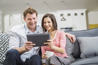 Caucasian couple using digital tablet on sofa
