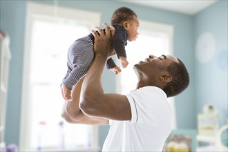 Black father lifting baby son