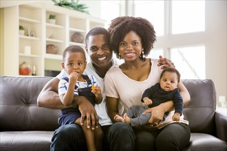 Smiling Black family posing on sofa