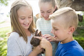 Caucasian boy and girls petting rabbit