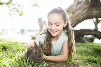 Caucasian girl petting rabbit