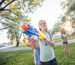 Caucasian girls playing with squirt guns