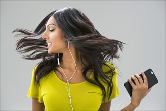 Carefree Indian woman tossing hair and listening to music