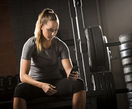 Caucasian woman texting on cell phone in gymnasium