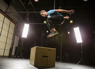 Caucasian man jumping on box in gymnasium