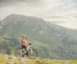 Caucasian woman with mountain bike drinking from backpack