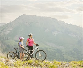 Caucasian grandmother and granddaughter standing with mountain bikes