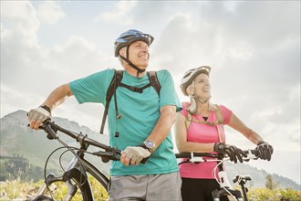 Caucasian couple standing with mountain bikes