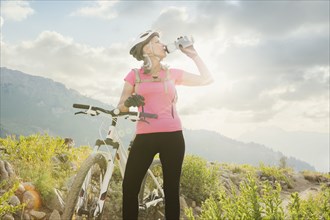 Caucasian woman with mountain bike drinking from bottle