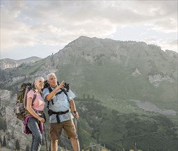 Caucasian couple with binoculars hiking on mountain